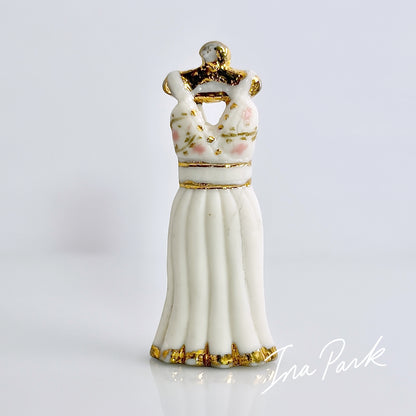 金色のハンガーにかかった白いドレスのフェーブ